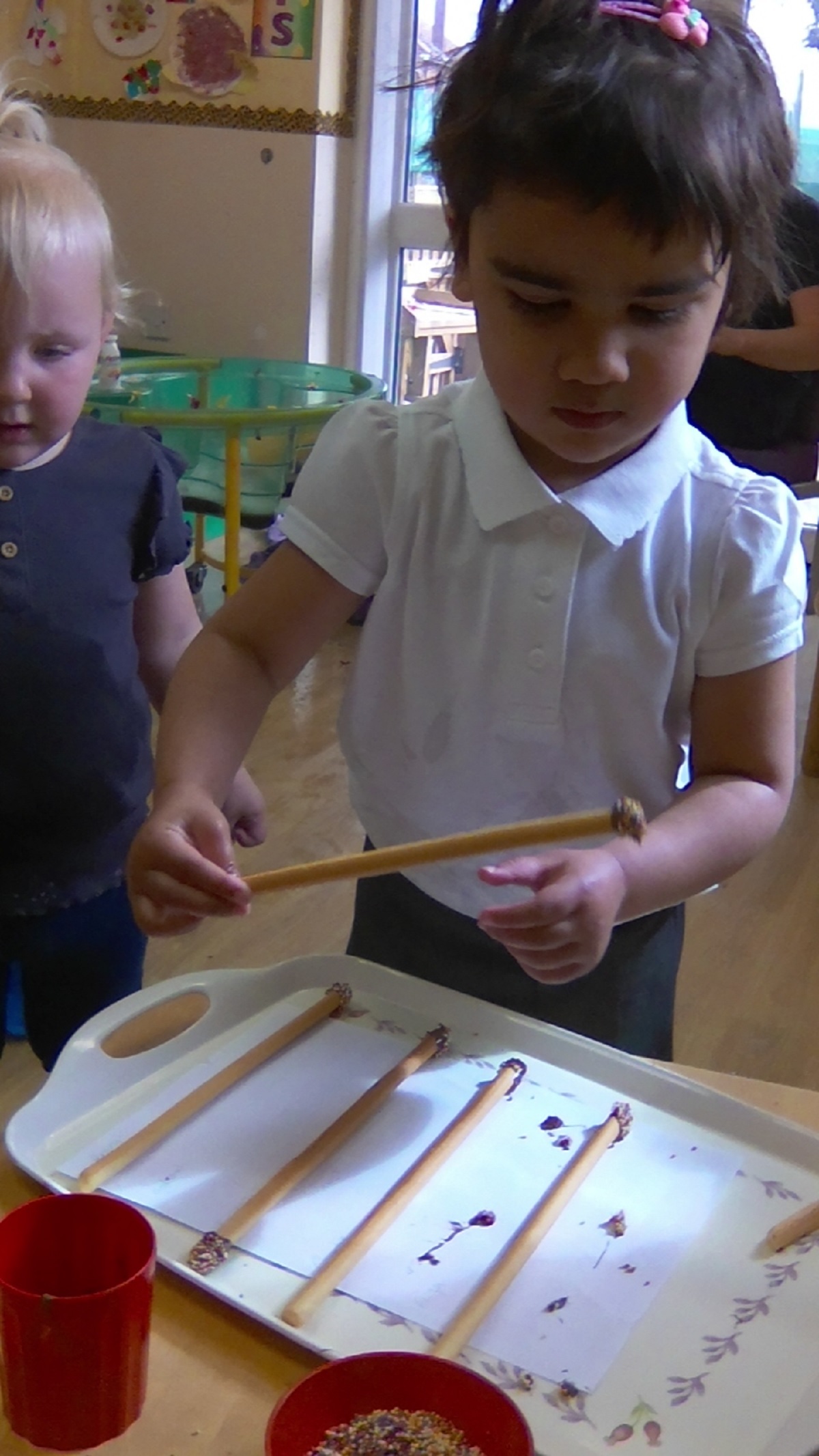 Spell the beans - Nursery children made edible magic wands using melted chocolate and sprinkles before using them to try to make spells. Pictured is Aalimah Ali and in the background is Eliza Nicholas